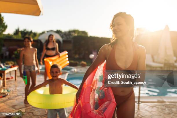 famiglia felice in piscina con galleggiante in mano. - bordo piscina foto e immagini stock