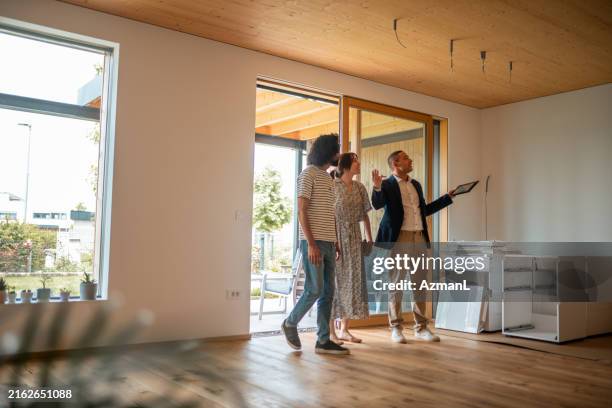hispanic real estate agent guides homebuyers during viewing - real estate agent stock pictures, royalty-free photos & images