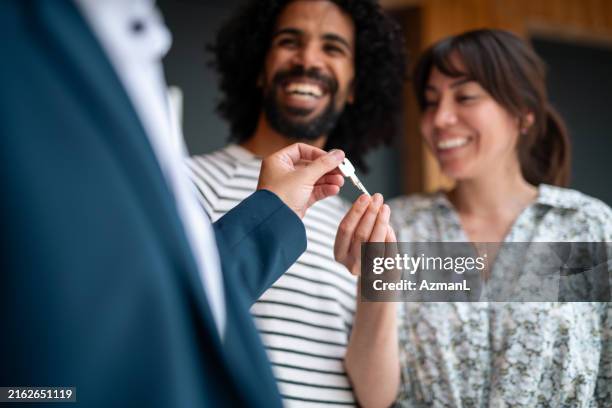 real estate agent gifting keys to joyful couple - corretor de imoveis imagens e fotografias de stock