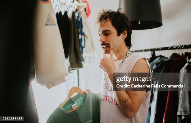 a stylish man looks at clothing - habilleuse styliste photos et images de collection