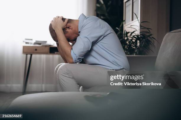 depressed mature man sitting on couch - suicide imagens e fotografias de stock