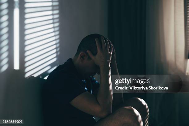 sad man sitting hand in face - mishandeling stockfoto's en -beelden