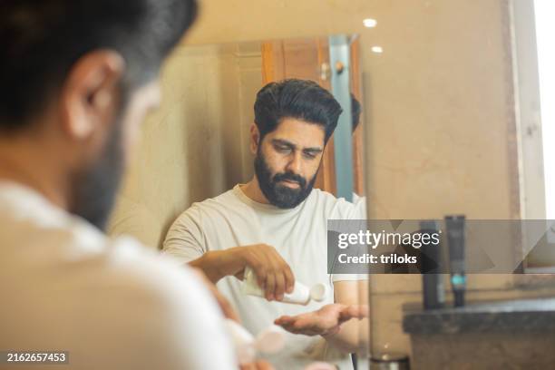 man with cream tube reflecting on bathroom mirror - beard stock pictures, royalty-free photos & images