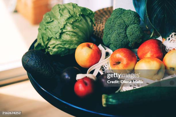 fresh organic fruits and vegetables in reusable mesh bag on kitchen at home - einkaufskorb stock-fotos und bilder