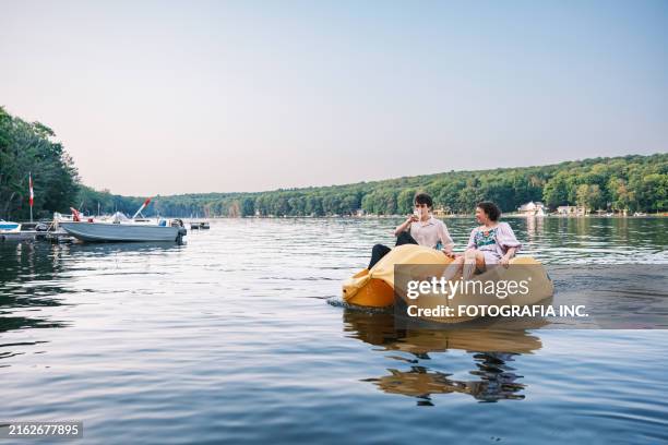 young couple enjoying paddle boat ride on the lake - paddleboat stock pictures, royalty-free photos & images