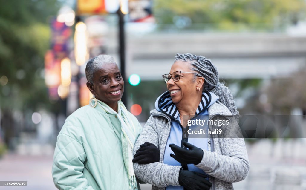 Two senior black women walking in city on cold day