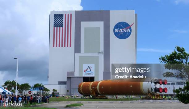 Workers transport the 212-foot-tall SLS core stage for the Artemis II moon rocket from the Pegasus barge to the nearby Vehicle Assembly Building at...