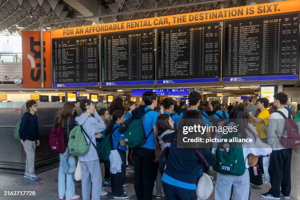 July 2024, Hesse, Frankfurt/Main: Travelers stand in front of a display board in the terminal at Frankfurt Airport, where numerous departures have...