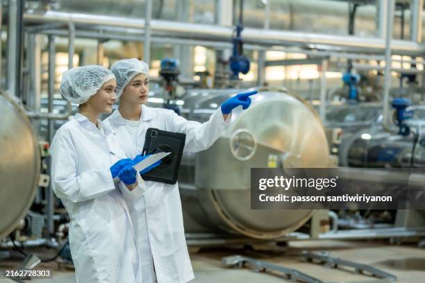 lebensmittelwissenschaftler, ernährungsberater oder qualitätskontrolleur tragen sie ein haarnetz und sterile kleidung. überprüfen sie die qualität von getränkeprodukten in der produktionslinie - produktionsstätte stock-fotos und bilder