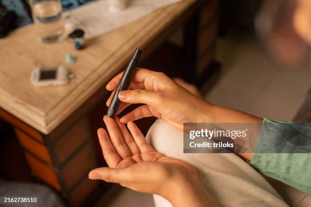 hands of woman examining her glucose with pen at home - glucose stockfoto's en -beelden