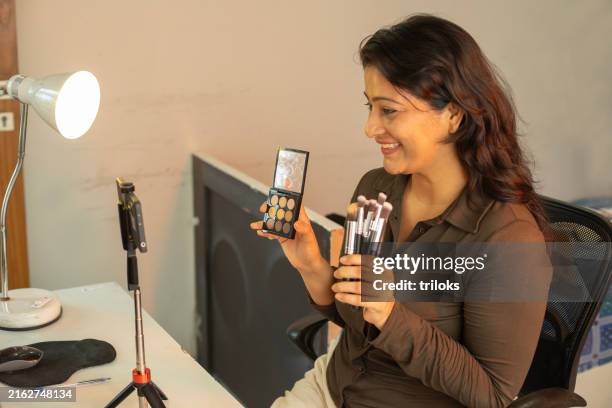 woman showing makeup kit while recording blog with phone at home - content creation stock pictures, royalty-free photos & images
