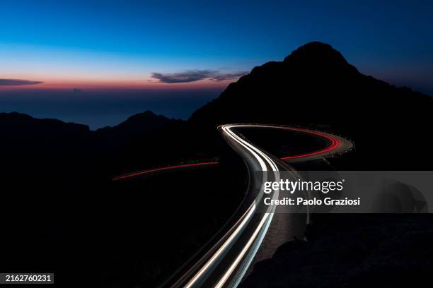 car trails lights on winding road, spain - light trail imagens e fotografias de stock
