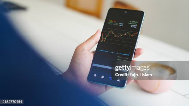 young man checking investment and stock with mobile app on smart phone - certificato azionario foto e immagini stock