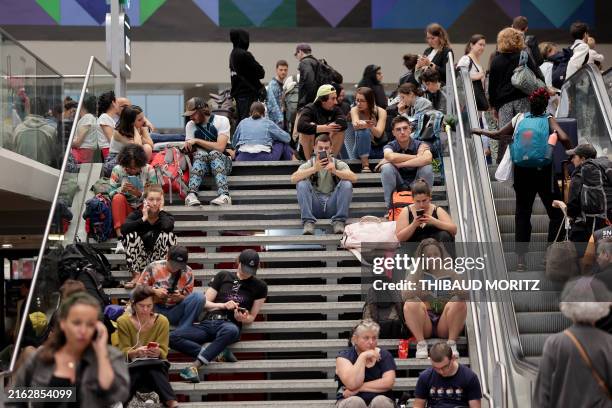 Passengers wait for their train departures at the Gare Montparnasse train station in Paris on July 26, 2024 as France's high-speed rail network was...