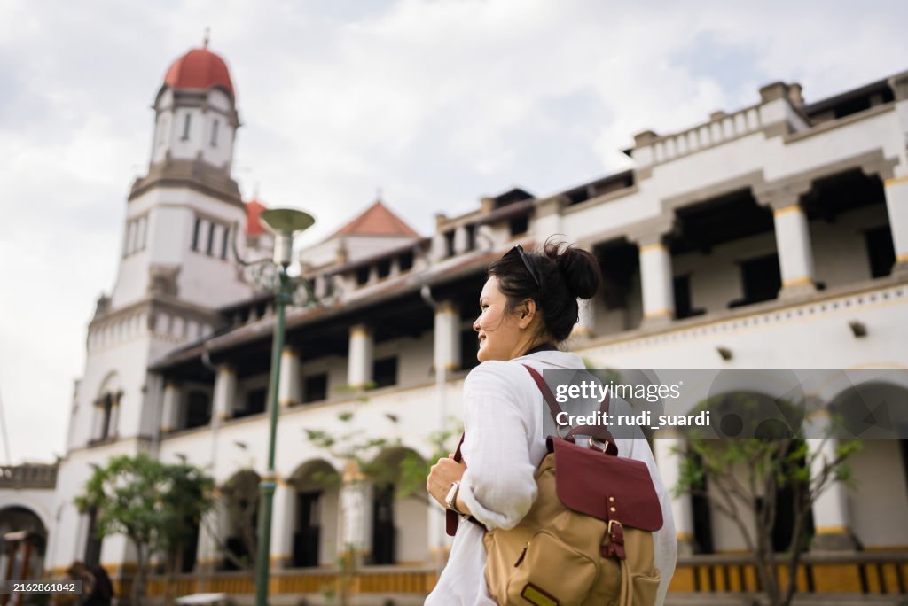 Adult tourist photographing lawang sewu the duct station in semarang with camera. He is wearing casual clothes and a backpack.