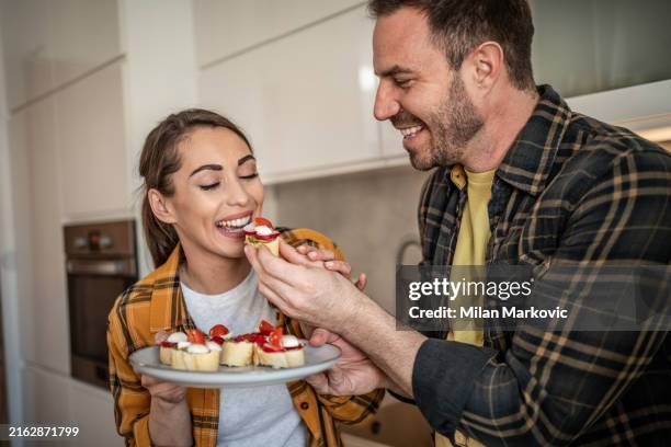 the couple enjoys bruschetta together in the kitchen - man ready to eat stock pictures, royalty-free photos & images