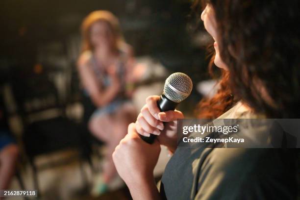 nahaufnahme mit einem mikrofon in der hand auf der bühne. - stand up comedy stock-fotos und bilder