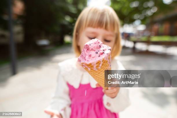glückliches süßes mädchen, das eis im sommerpark genießt - girl eating messy ice cream cone stock-fotos und bilder