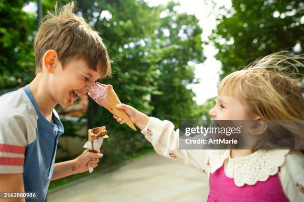 cute children having fun with ice-cream in summer park - girl eating messy ice cream cone stock pictures, royalty-free photos & images