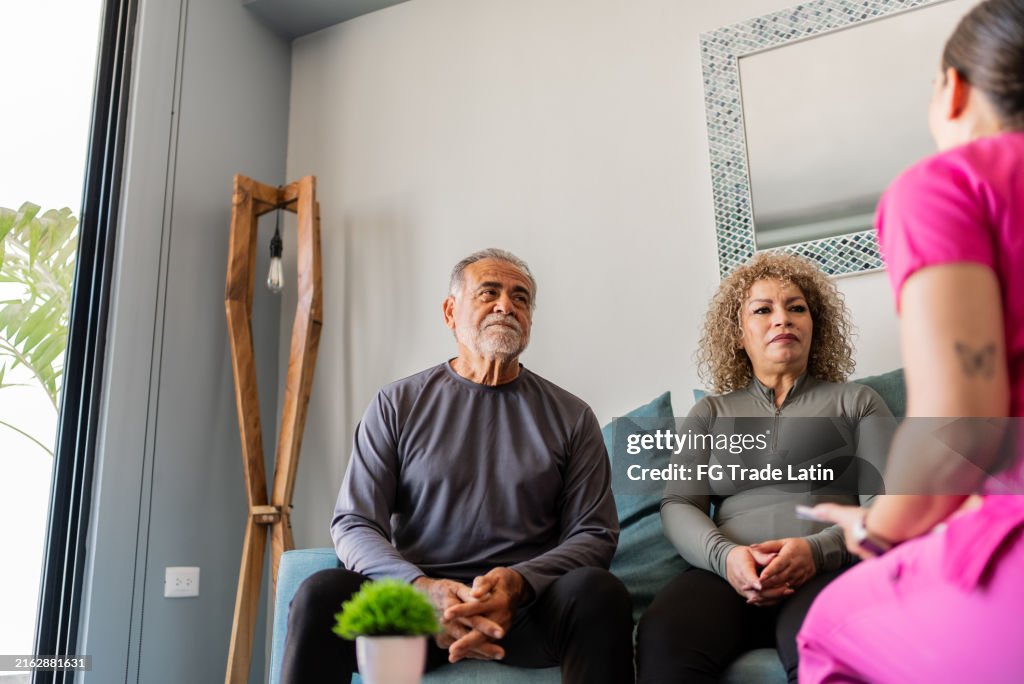 Physical therapist talking to senior couple at house call