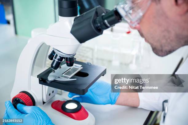 research and development laboratory for a sustainable future. close-up shot of a male scientist or researcher analyzing a scientific sample through a microscope in a laboratory. - medical technologist stock pictures, royalty-free photos & images
