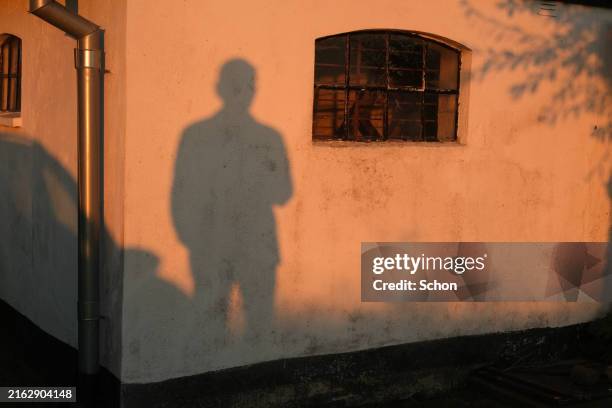the shadow of a man on a white barn in the evening sun - july stock pictures, royalty-free photos & images