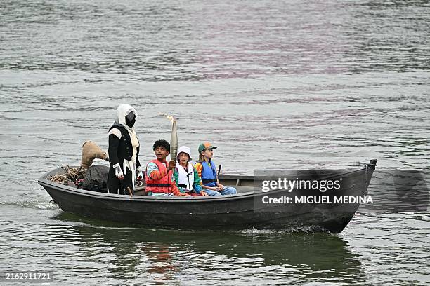 The torch bearer holds the Olympic Torch on a boat during the opening ceremony of the Paris 2024 Olympic Games in Paris on July 26, 2024.
