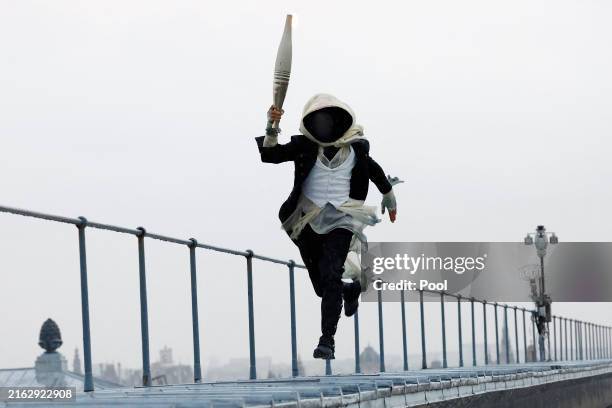 Torchbearer runs atop the Musee d'Orsay during the Opening Ceremony of the Olympic Games Paris 2024 on July 26, 2024 in Paris, France.
