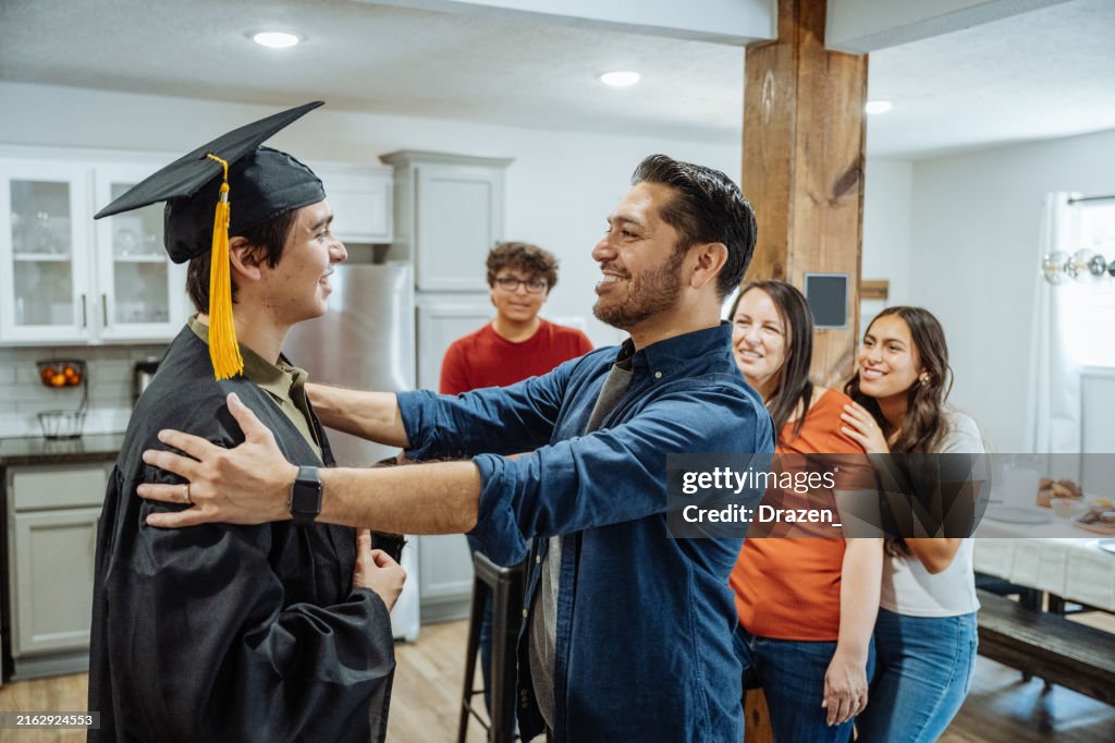 Graduation Dad Graduation Celebration At Home Father Hugging Son In Graduation Gown ...