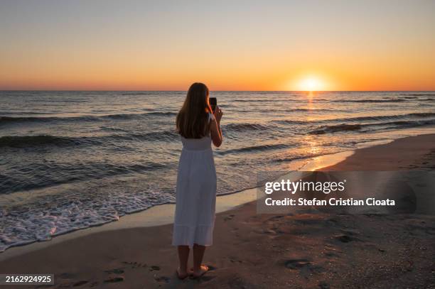 girl taking photos at sunrise on a beach in vadu, constanta, romania - constanta stock pictures, royalty-free photos & images