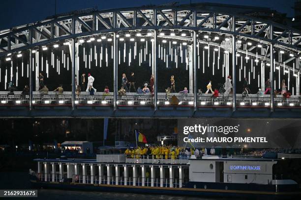 Models present creations while walking a catwalk erected along the Passerelle Debilly bridge as the boat carrying the delegations of Romania and...