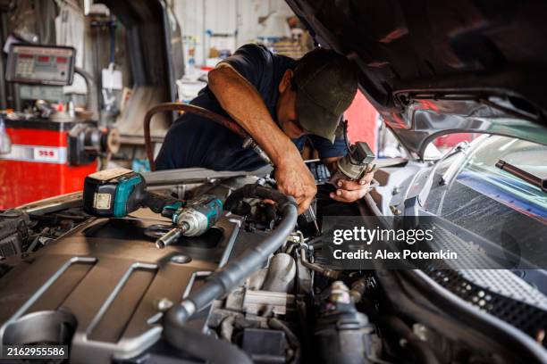 delving into automotive intricacies. middle-aged latino mechanic performs engine diagnosis and repair. - intricacy stock pictures, royalty-free photos & images