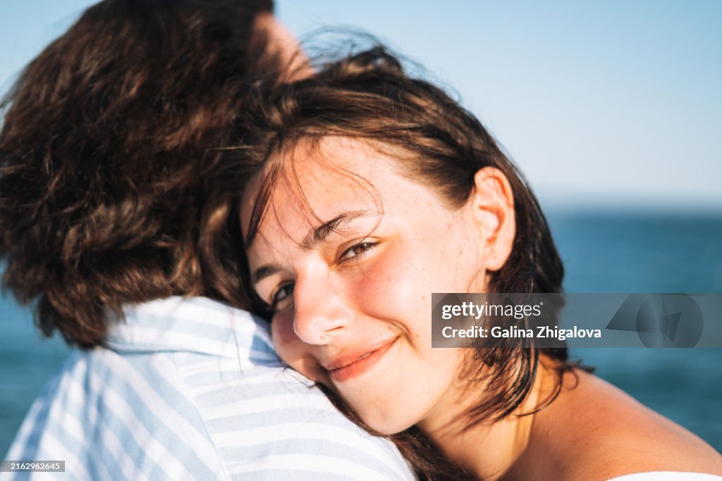 Close up portrait of smiling teenage girl hugging her mother against the background of seascape