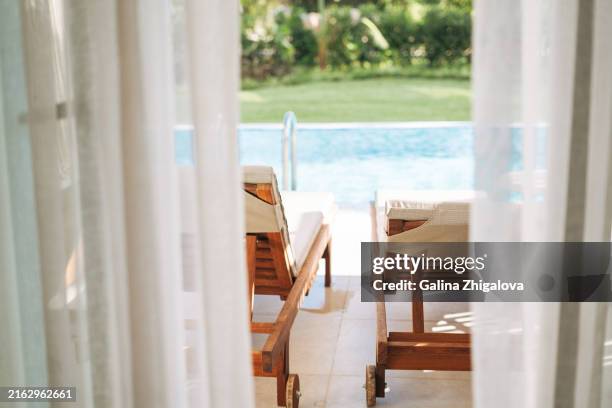 the view from hotel room through the curtains to sun beds and pool - casa al mare foto e immagini stock