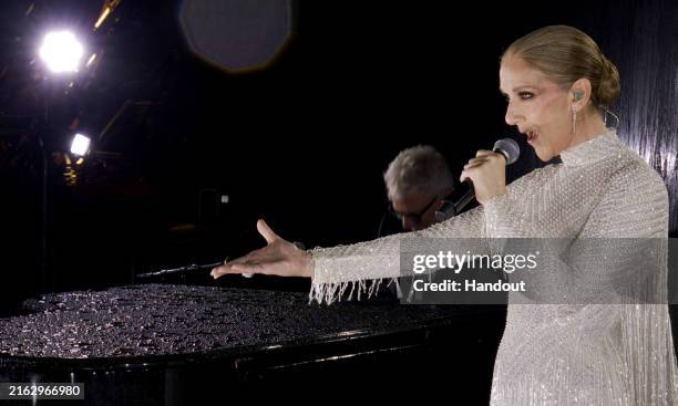 This handout released by the Olympic Broadcasting Services, shows a view of singer Celine Dion performing on the Eiffel Tower during the opening...