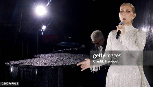 This handout released by the Olympic Broadcasting Services, shows a view of singer Celine Dion performing on the Eiffel Tower during the opening...
