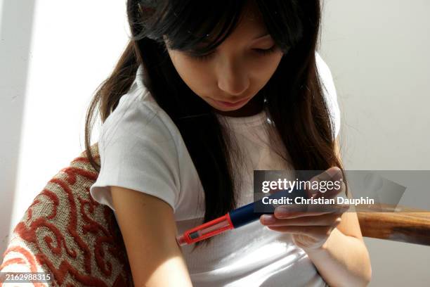 a mixed-race teenager injecting insulin with insulin pen. - compromised immune system stock pictures, royalty-free photos & images