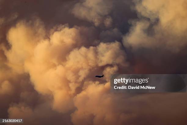Firefighting jet passes as a massive pyrocumulus cloud rises from the Park Fire, which has grown to 239,152 acres and is 0 percent contained, expands...