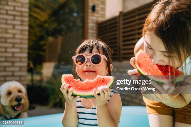 young asian toddler girl refreshing with watermelon slice with her mother in backyard - familia de verdad fotografías e imágenes de stock