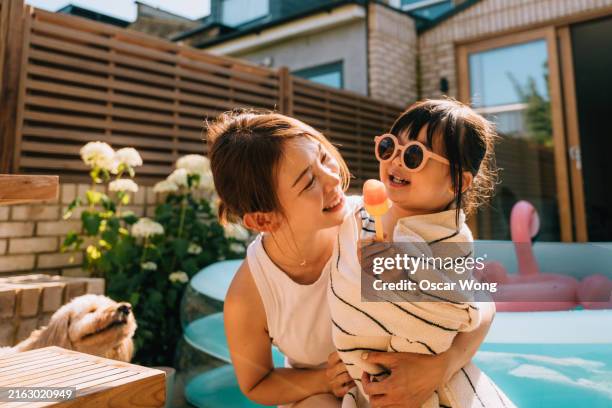caring young asian mother wrapping her toddler daughter in towel after swimming - in ein handtuch gewickelt stock-fotos und bilder