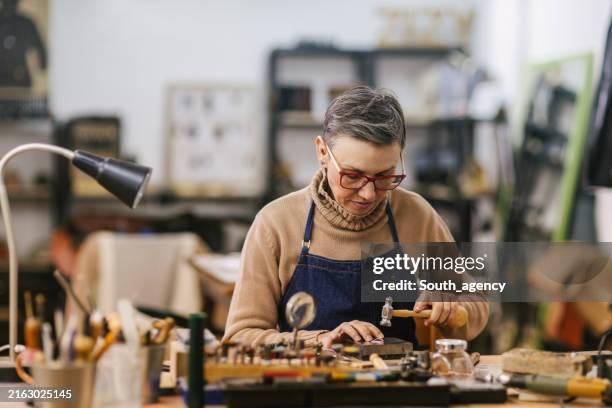 craftsperson working on jewelry piece at workbench. - juwelier stockfoto's en -beelden