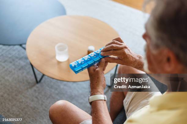 älterer kaukasischer mann, der medikamente organisiert - tablettenschachtel stock-fotos und bilder