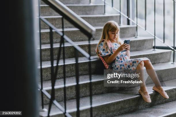 junges mädchen mit smartphone auf schultreppe - aula stock-fotos und bilder