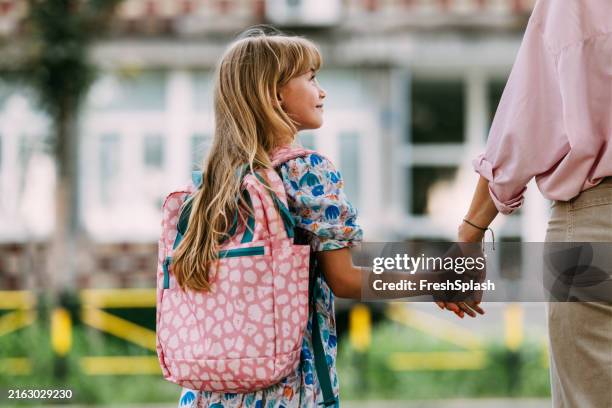 mutter hält tochter an der hand am ersten schultag - beginn des schuljahres stock-fotos und bilder