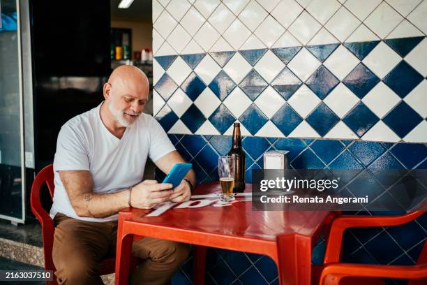 senior man using smart phone at bar - brazilian culture stock pictures, royalty-free photos & images