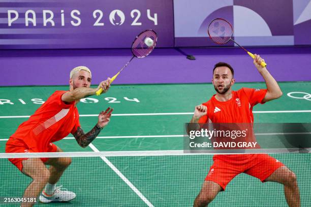 Britain's Ben Lane hits a shot next to Sean Vendy in their men's doubles badminton group stage match during the Paris 2024 Olympic Games at Porte de...