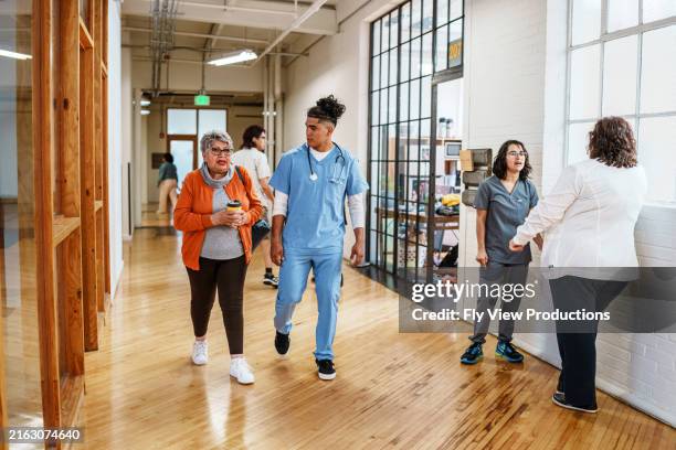 male nurse walks down hospital hallway with his senior patient - hospital team with patient stock pictures, royalty-free photos & images