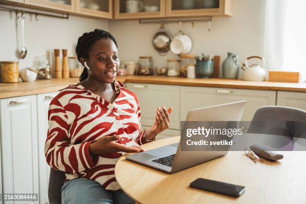 young pregnant woman working on laptop at kitchen - wireless headphones stock pictures, royalty-free photos & images