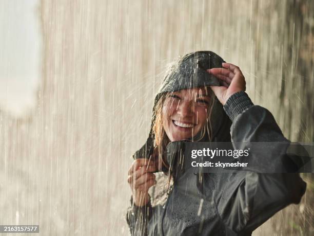 femme heureuse en imperméable debout sur une pluie dans la nature. - vêtement de pluie photos et images de collection