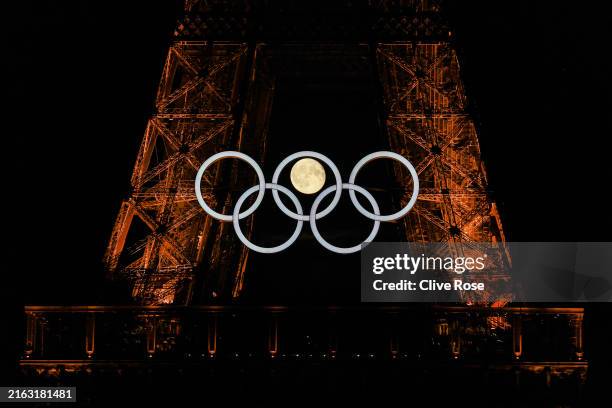 The moon rises behind the Eiffel Tower and the Olympic Rings ahead of the Paris 2024 Olympic Games on July 22, 2024 in Paris, France.